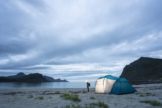 Noruega, Lapônia, Pessoa em pé junto à tenda em uma praia no fiorde — Fotografia de Stock