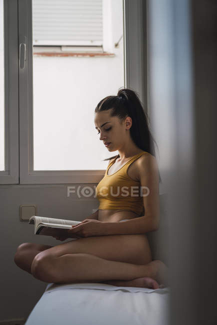 Giovane donna in biancheria intima libro di lettura a casa — Foto stock