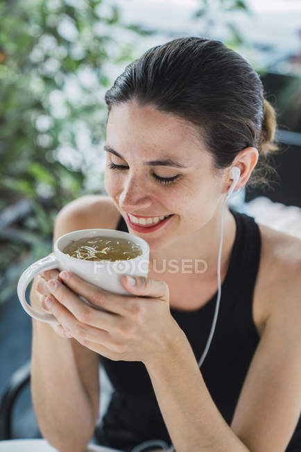 Молода жінка сидить у кав'ярні та п'є чай — стокове фото