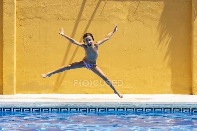 Felice bambina saltando in piscina — Foto stock
