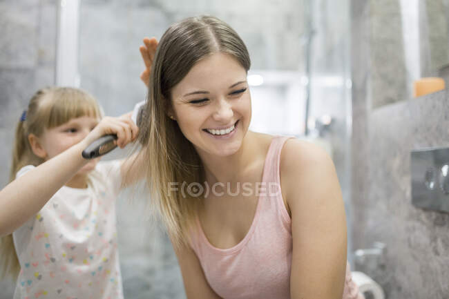 Menina escovando o cabelo de sua mãe — Fotografia de Stock