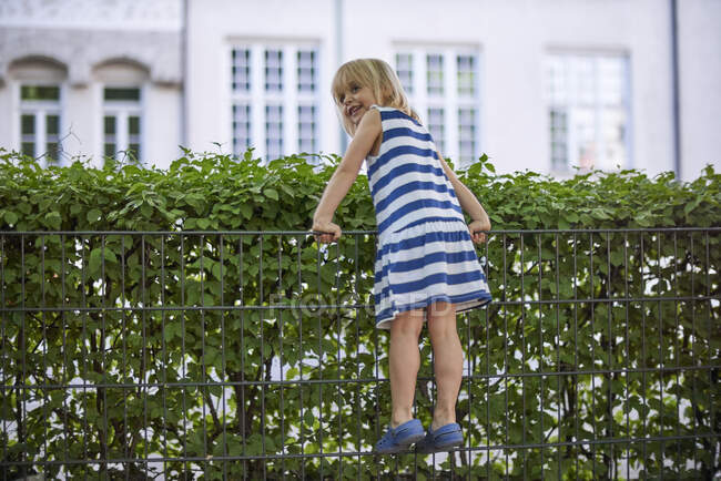 Smuling bambina arrampicata sulla recinzione — Foto stock