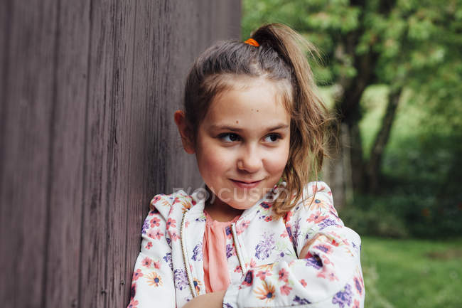 Portrait de fille souriante appuyée contre un mur en bois — Photo de stock