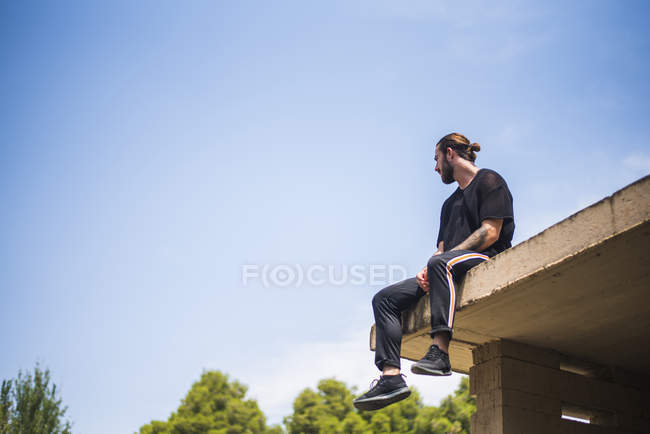 Tattooed man sittin on roof top — Stock Photo