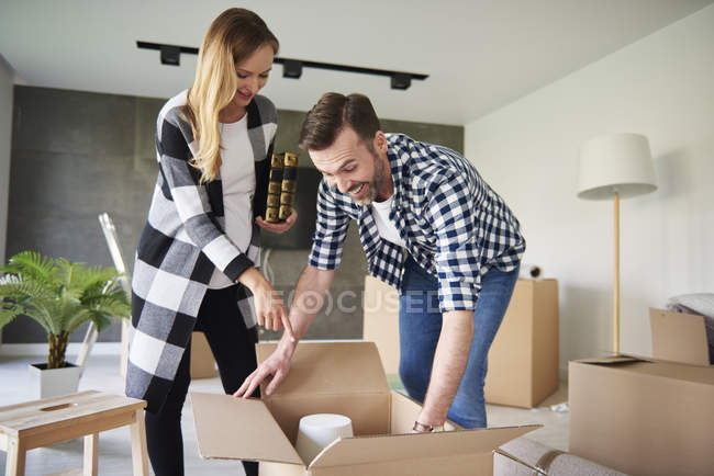 Casal feliz movendo-se para novo apartamento desembalagem caixa de papelão — Fotografia de Stock