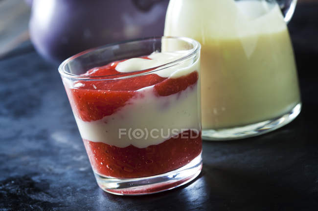 Compota de frutas rojas con salsa de vainilla en capas en un vaso - foto de stock