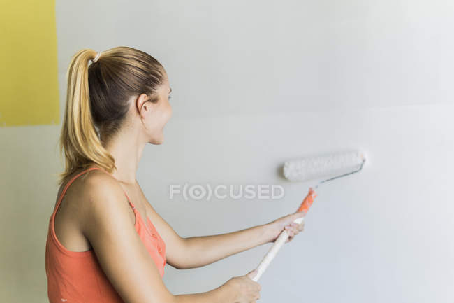 Jeune femme mur de peinture à la nouvelle maison — Photo de stock