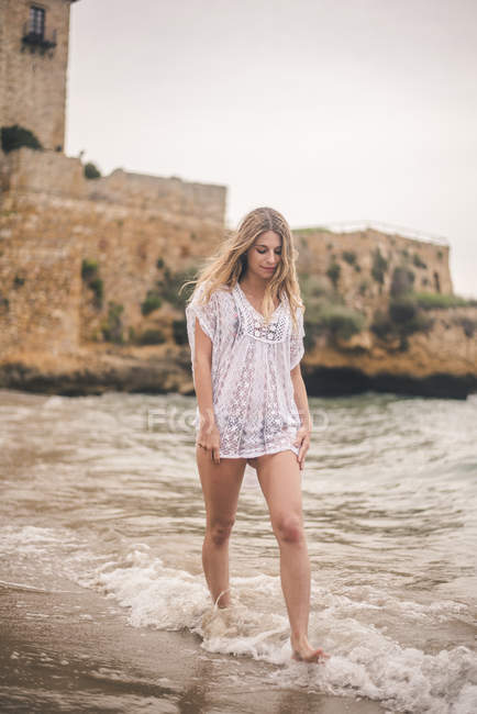 Schöne junge Frau watet im Wasser am Strand — Stockfoto