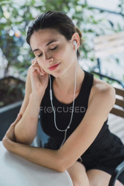 Giovane donna d'affari seduta in caffetteria e ascoltare musica — Foto stock