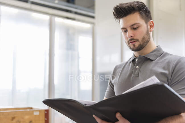 Человек смотрит на папку на заводе — стоковое фото