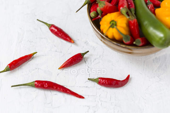 Cinque baccelli di peperoncino rosso e ciotola di vari peperoncini — Foto stock