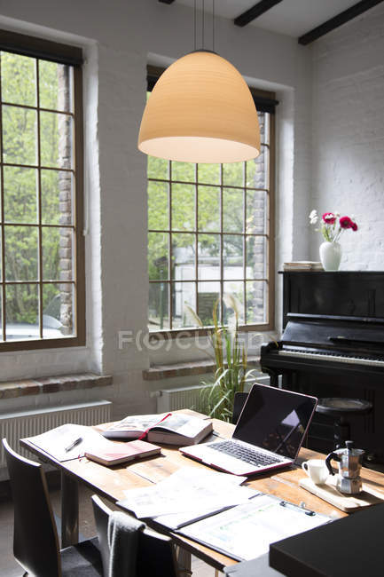 Home office con pianoforte in sottofondo in confortevole loft — Foto stock