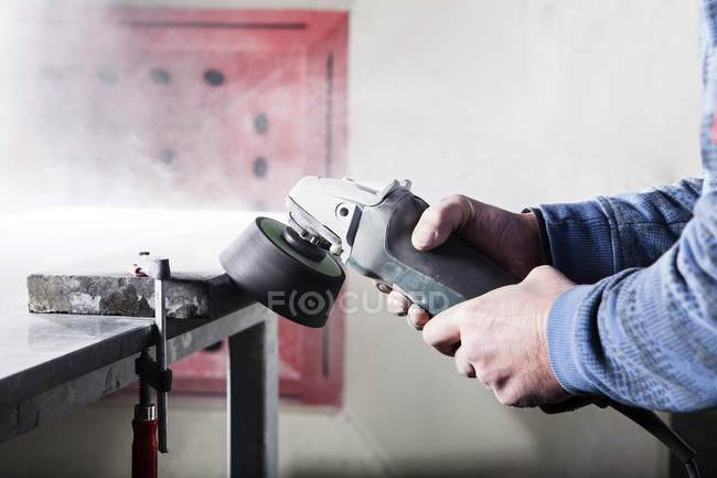 Stonemason working on stone with a grinding machine in his workshop — Stock Photo