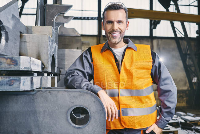 Portrait d'un homme souriant portant des vêtements de travail protecteurs dans une usine — Photo de stock