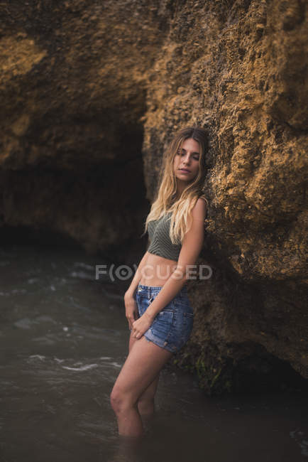 Bela jovem mulher de pé em uma rocha no mar — Fotografia de Stock