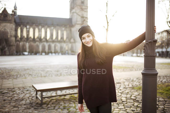 Porträt einer lächelnden jungen Frau bei Gegenlicht in der Stadt — Stockfoto