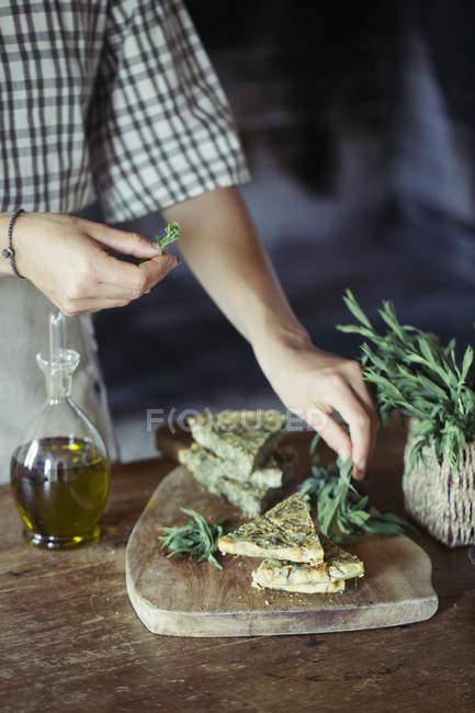 Giovane donna guarnire ceci fatti in casa e torta di erbe — Foto stock