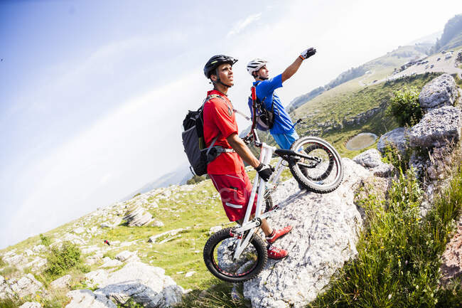 Motociclistas acrobáticos con bicicletas de trial en roca - foto de stock