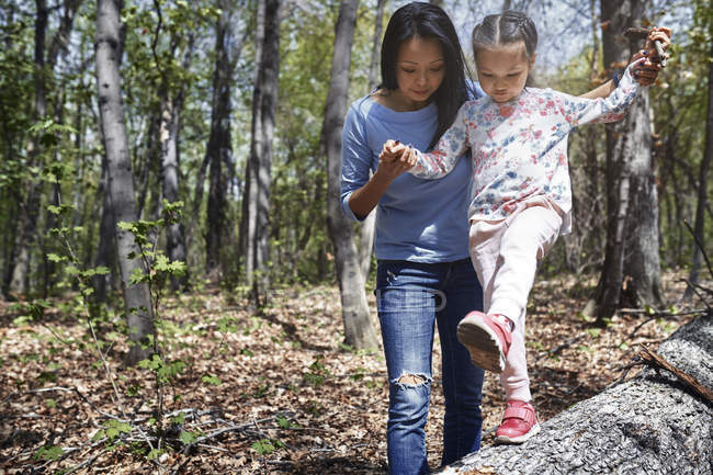 Madre e figlia nel parco, ragazza in equilibrio sul tronco d'albero — Foto stock