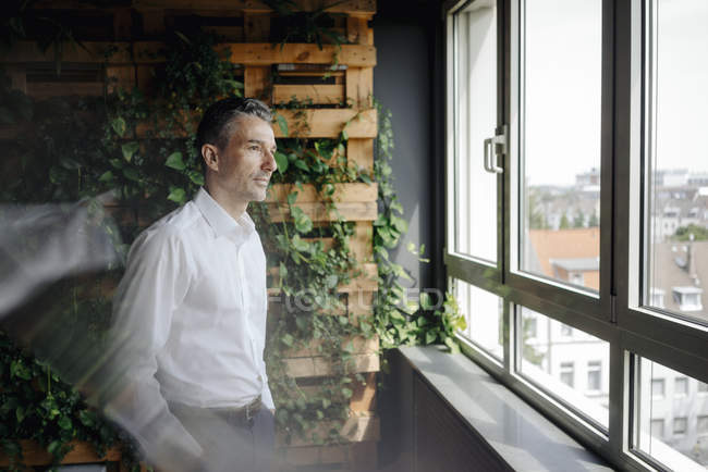 Geschäftsmann im grünen Büro schaut aus dem Fenster — Stockfoto