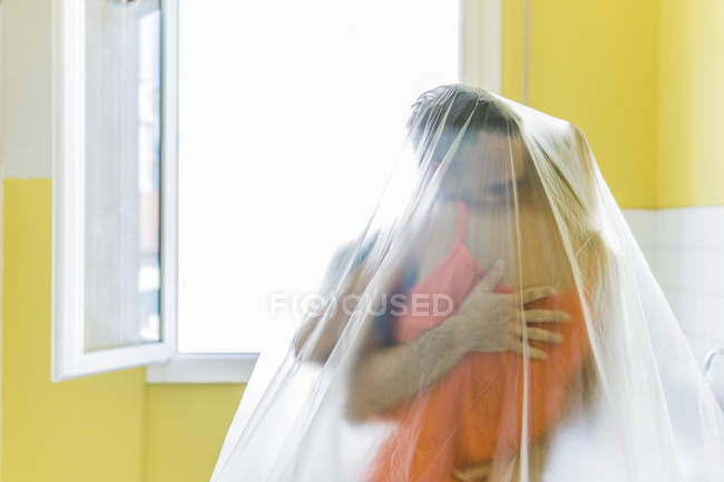 Baciare coppia sotto pellicola di plastica a casa nuova — Foto stock