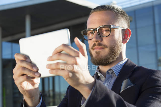 Businessman holding a tablet in city and looking at camera — Stock Photo