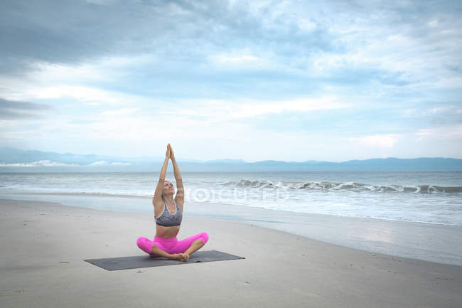 Mujer practicando meditación de yoga en la playa - foto de stock