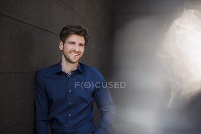 Portrait of smiling businessman leaning against wall — Stock Photo