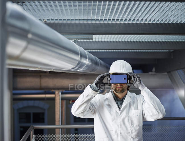 Técnico con sombrero duro mirando a través de gafas VR - foto de stock