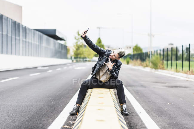 Punk donna seduta a bordo strada in posa per selfie — Foto stock