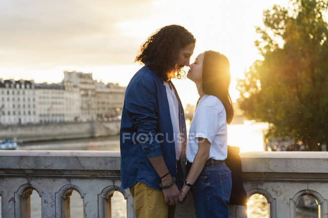 Frankreich, Paris, liebevolles junges Paar am Fluss Seine bei Sonnenuntergang — Stockfoto