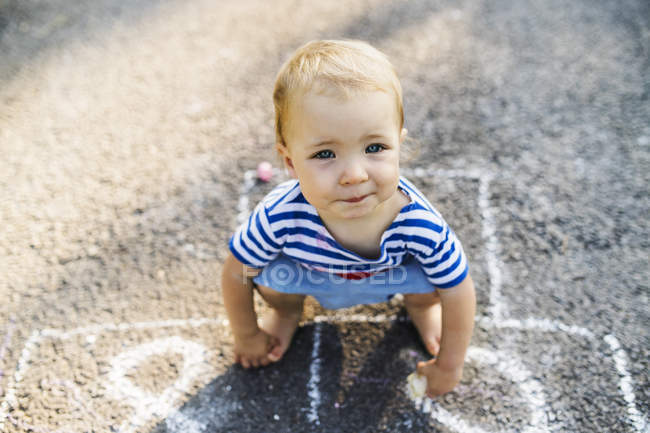 Portrait of baby girl crouching barefoot on asphalt — Stock Photo