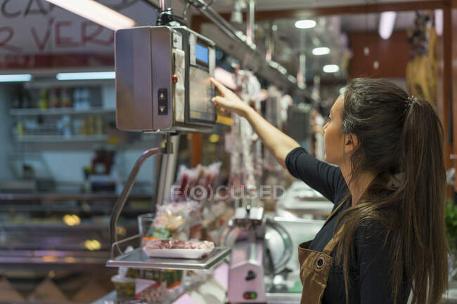Macellaio donna che pesa salsiccia su bilancia — Foto stock