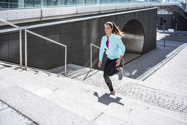 Mujer joven corriendo por las escaleras de la ciudad - foto de stock