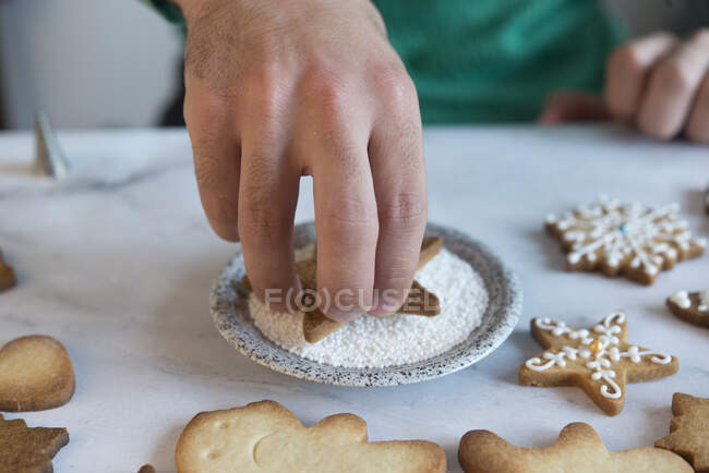 Man's hand decorating Christmas Cookie, close-up — Stock Photo