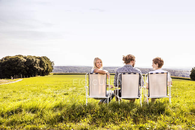 Friends sitting on camping chairs in rural landscape — Stock Photo