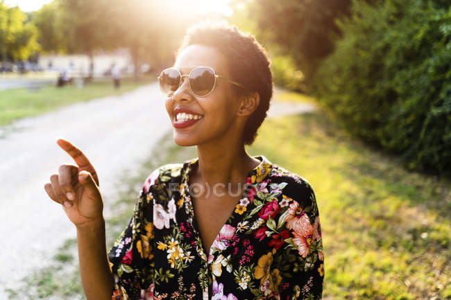 Happy young woman wearing sunglasses outdoors at sunset — Stock Photo