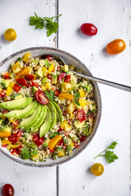 Bowl of bulgur salad with bell pepper, tomatoes, avocado, spring onion and parsley — Stock Photo