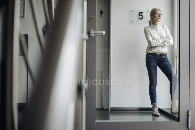 Donna d'affari in piedi sul corridoio guardando fuori dalla finestra — Foto stock