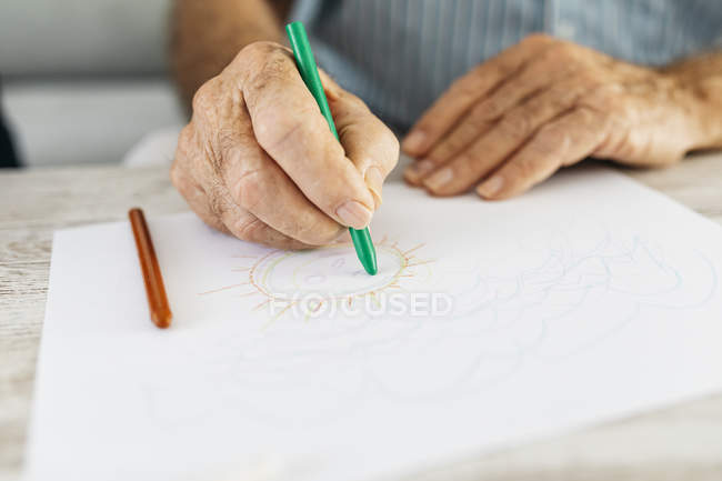 Senior man's hand drawing with green pencil, close-up — Stock Photo