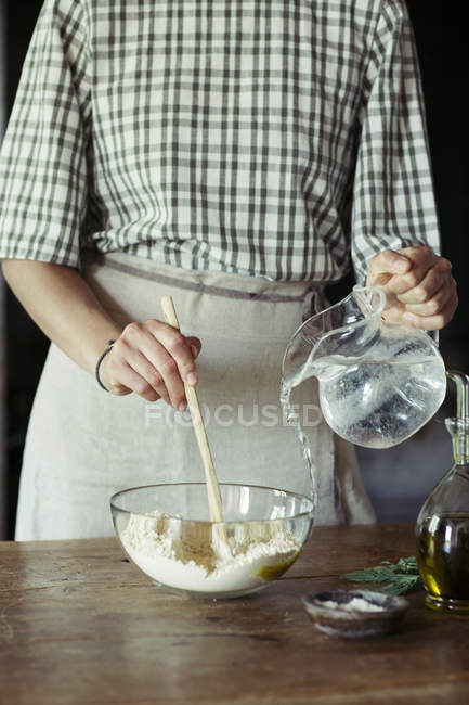 Mujer joven en la cocina preparando masa para pastel de garbanzos frescos - foto de stock