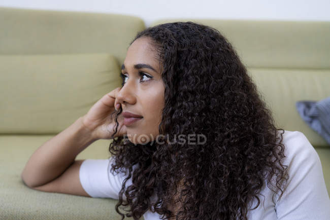 Giovane donna seduta a casa, pensando — Foto stock