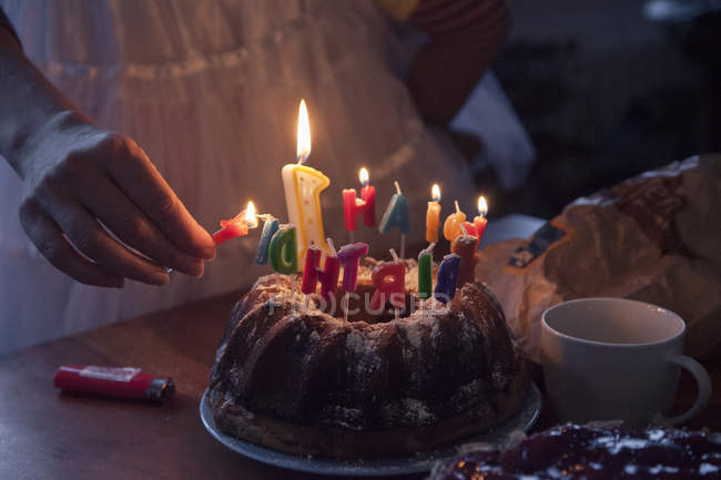 Frau zündet Geburtstagskuchenkerzen an, Teilansicht — Stockfoto