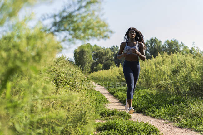 Atleta joven corriendo en el campo verde - foto de stock