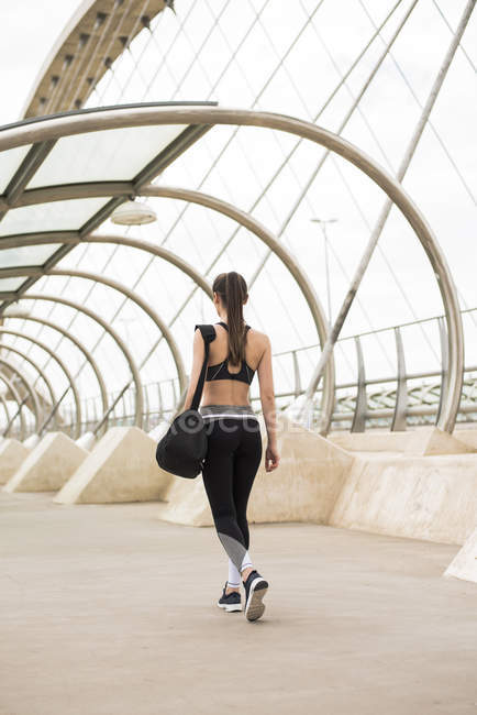 Спортивная женщина с спортивной сумкой ходьба, вид сзади — стоковое фото
