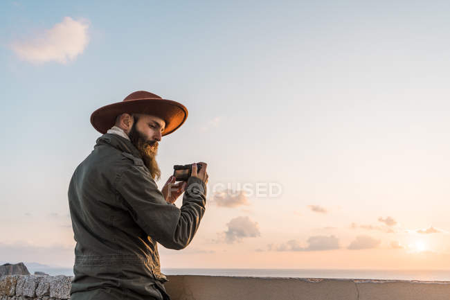 Italia, Sardegna, uomo che scatta foto con macchina fotografica al tramonto — Foto stock