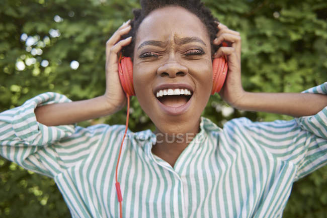 Portrait of singing young woman with headphones — Stock Photo