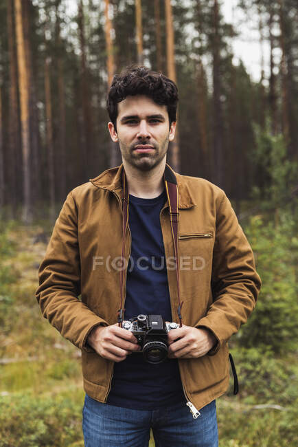 Finnland, Lappland, Porträt eines jungen Mannes mit Kamera in ländlicher Landschaft — Stockfoto