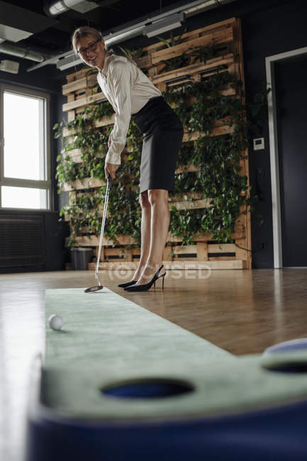 Бизнесмен, играющая в гольф в офисе — стоковое фото