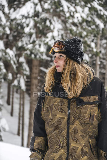 Молода жінка в лижному одязі в зимовому лісі дивиться вбік — стокове фото